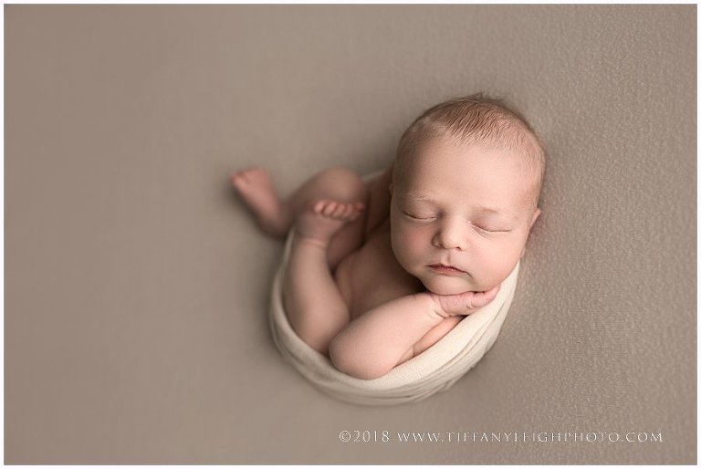 A baby is wrapped tight in a white blanket. 