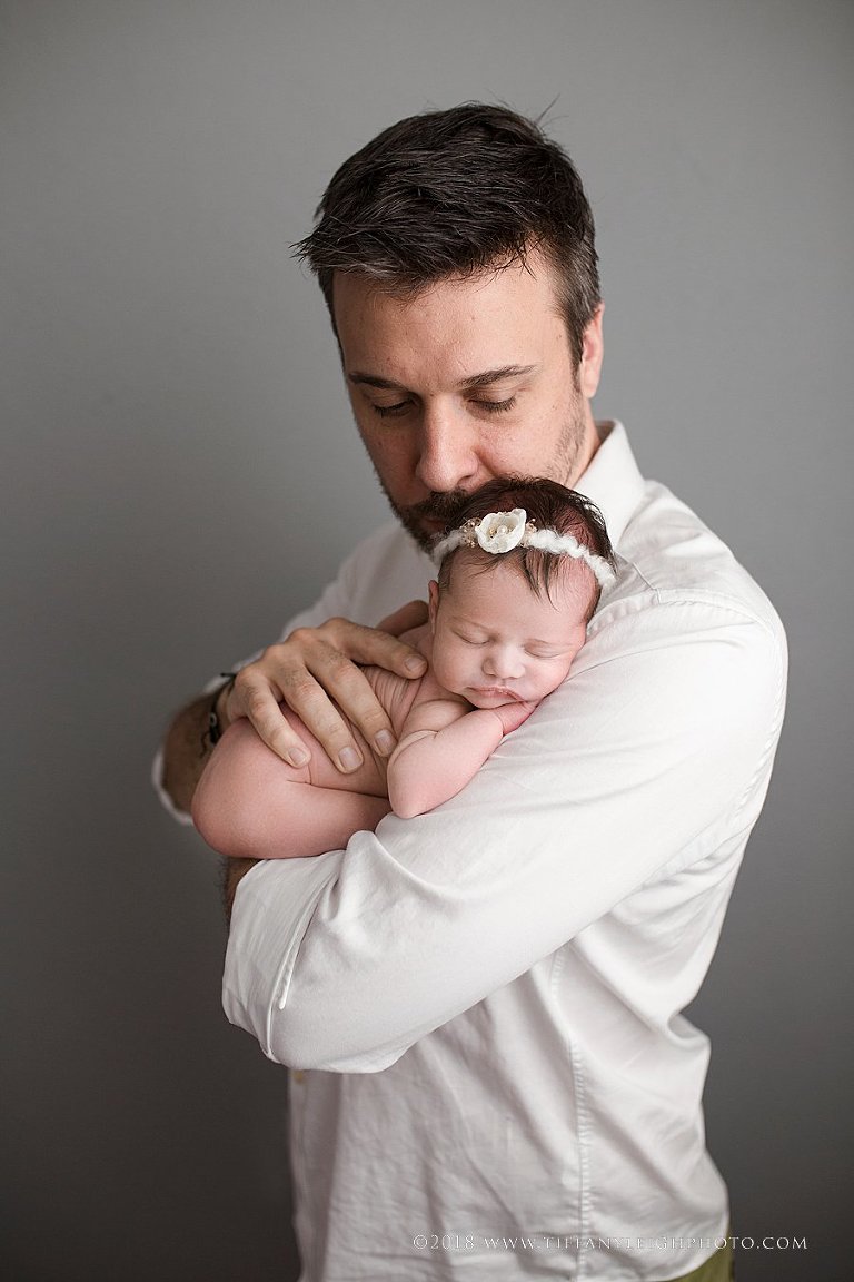 A new daddy holds his baby girl close. 