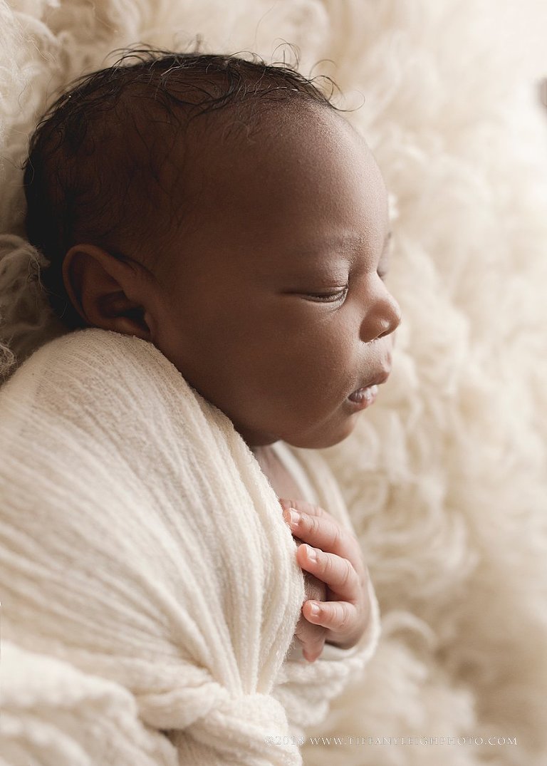 A baby sleeps while swaddled. 