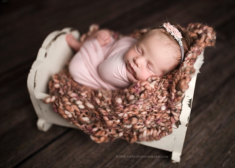 A baby sleeps in a tiny cradle
