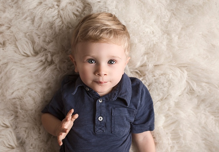 A little boy lays on a fluffy blanket