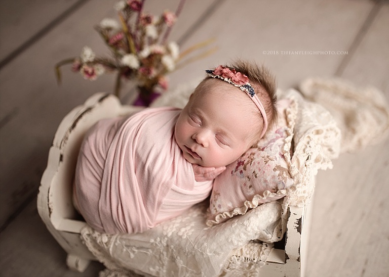 A baby is swaddled in a pink blanket