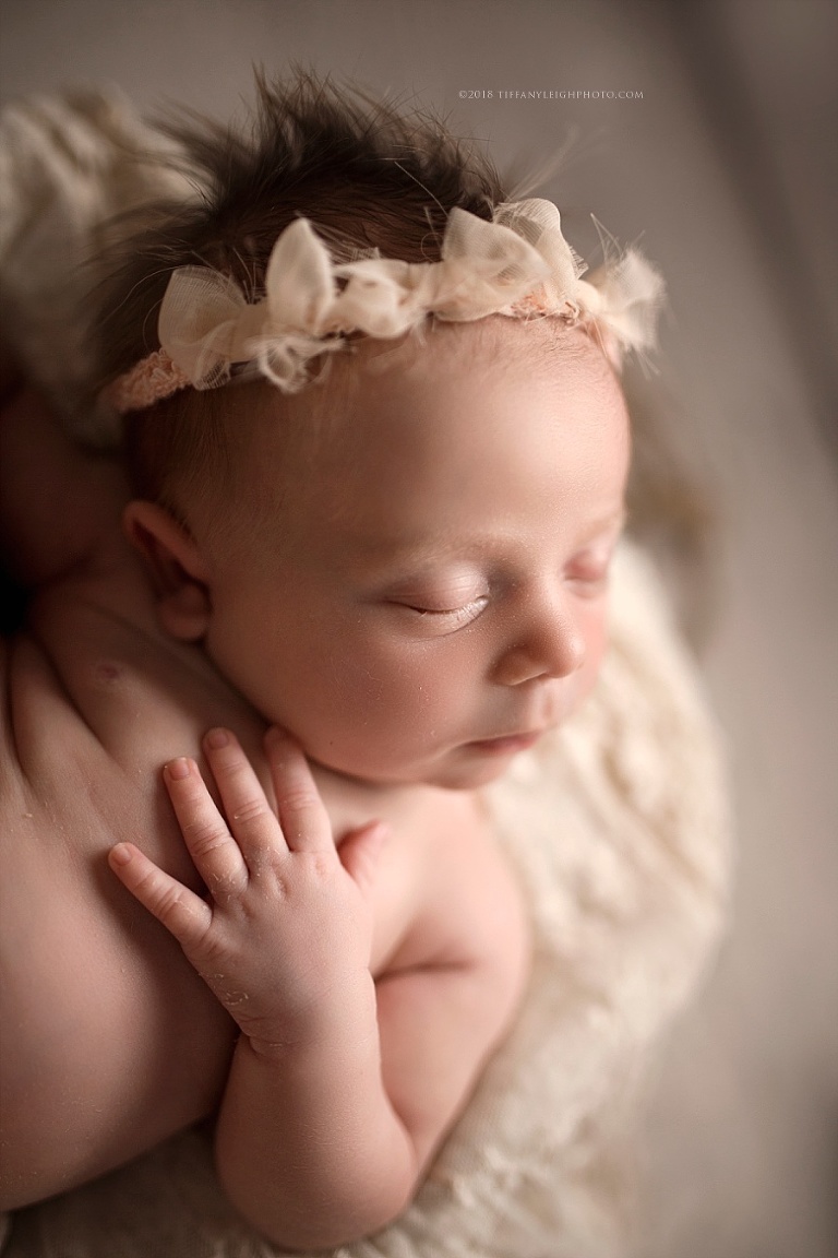 A baby sleeps with her hands on her chest