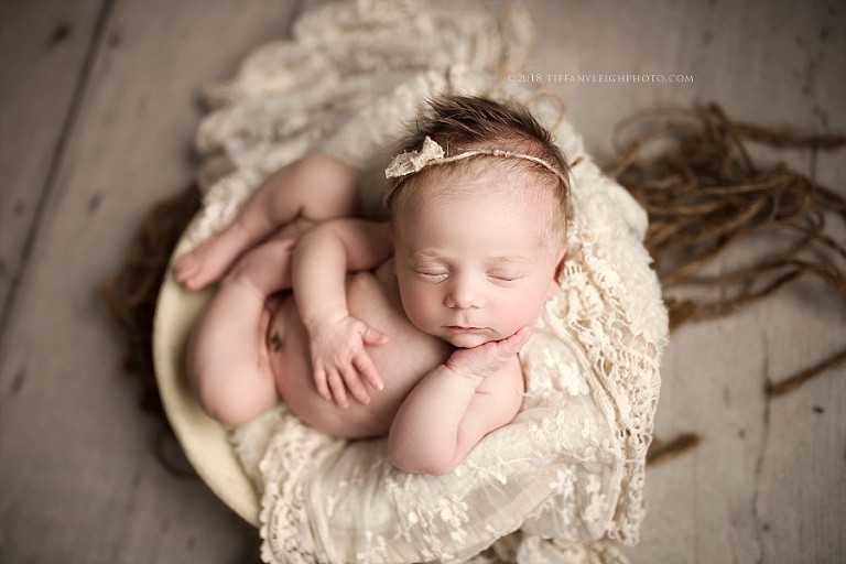 A newborn sleeps in a tiny basket. 