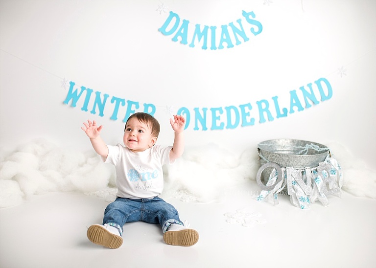A boy sits in front of his birthday decorations. 