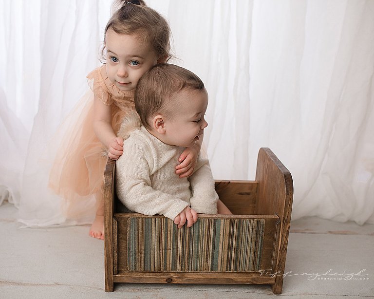 baby boy and older sister hugging