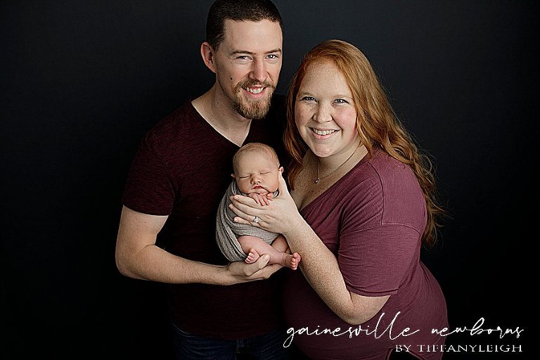 super proud mom and dad holding baby 